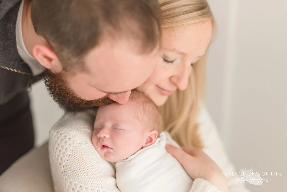 mom holds sleeping baby as dad kisses his head in grimsby