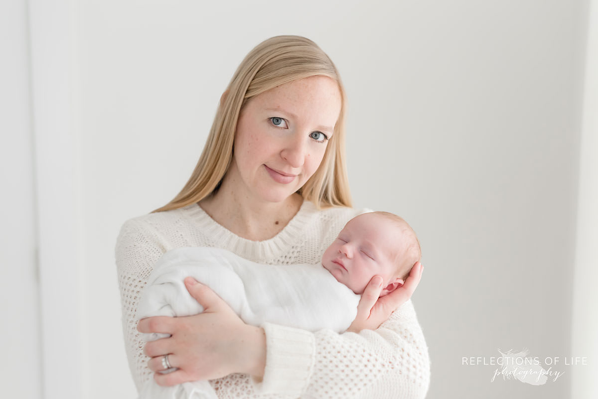 Mom looks at the camera as baby sleeps in her arms in niagara