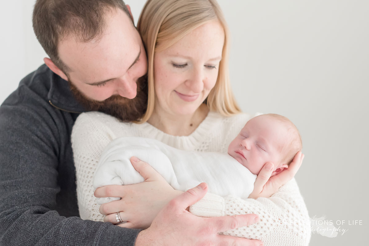 mom and dad cradle their beautiful son in natural light studio