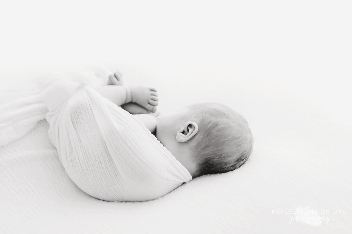 Baby sleeps swaddled facing the other way in black and white