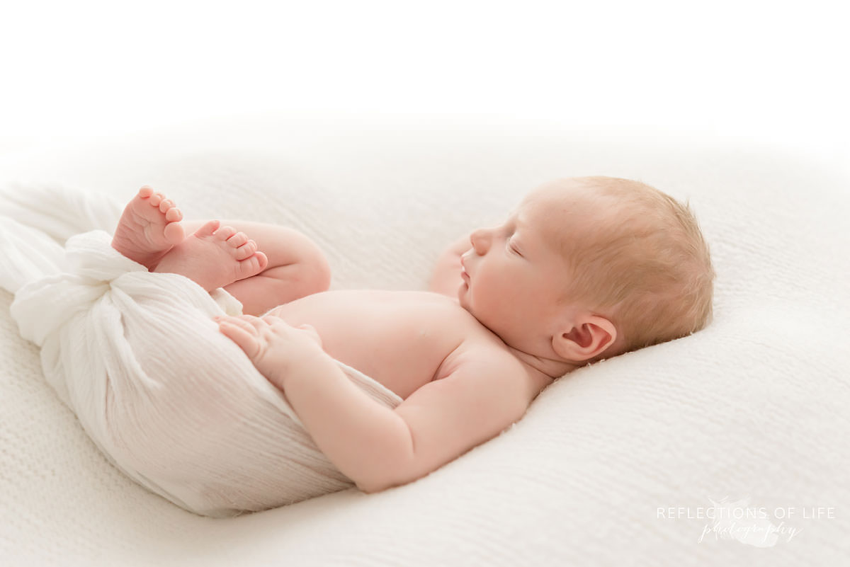 cute baby chills on white blanket in black and white