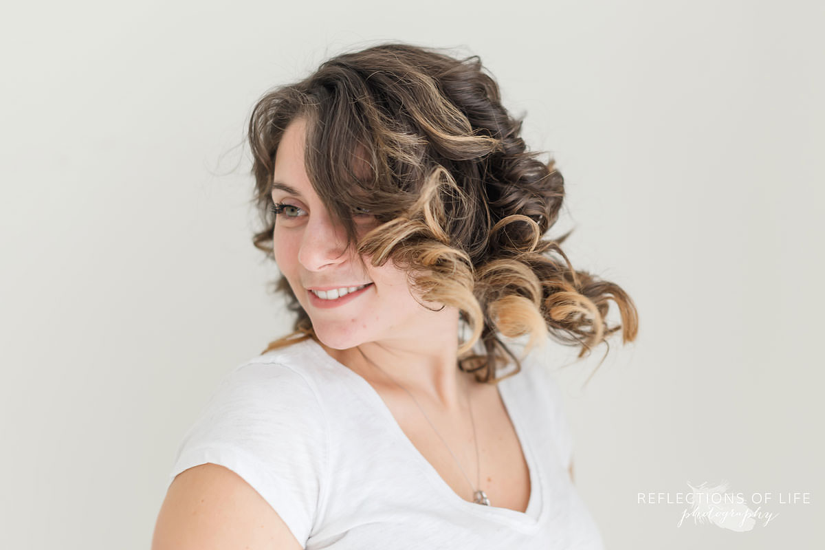newborn photographer kayla flips her hair in natural light studio