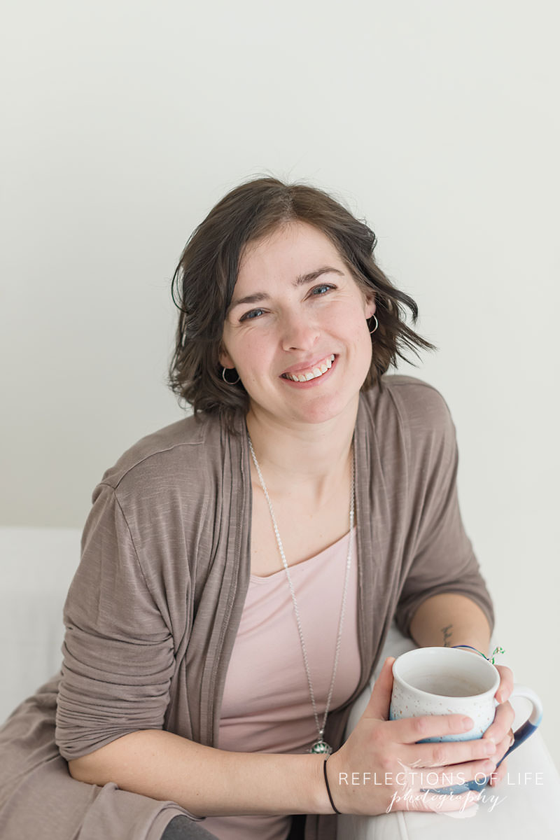 pretty lady smiles at the camera while holding her tea