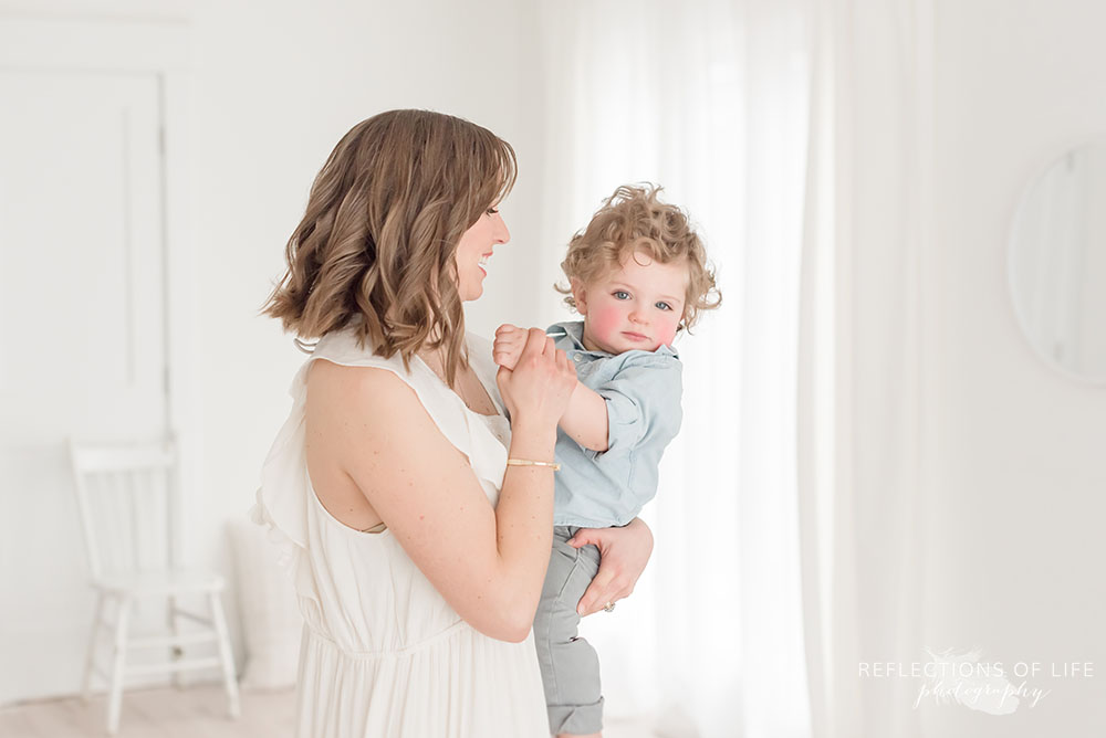 mama holds sons hand as he peeks at the camera in ontario