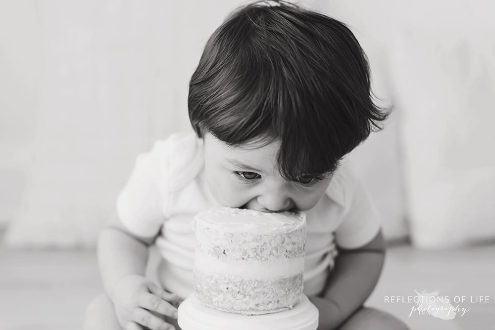toddler takes big bite out of cake in black and white