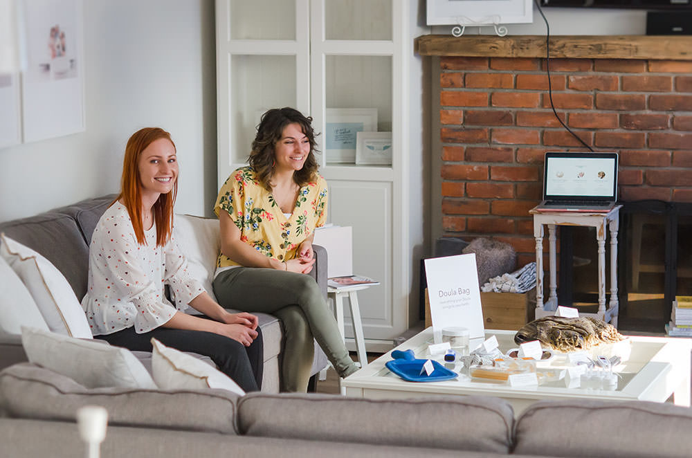 kayla and friend sit on the couch smiling