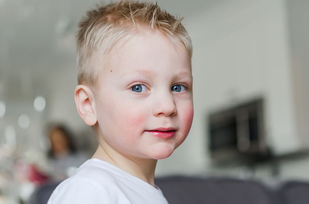 cute little boy smiles at the camera with bright blue eyes