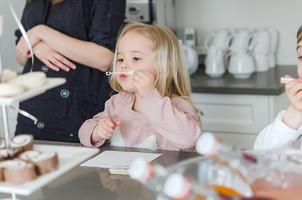 cute girl blows bubbles at the kitchen island
