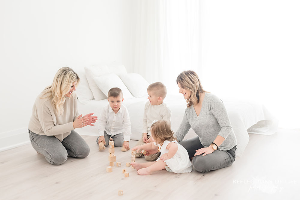 family of five play with blocks on the ground of natural light studio