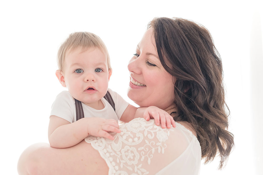 baby boy gives slight smile while looking at the camera being held by mama