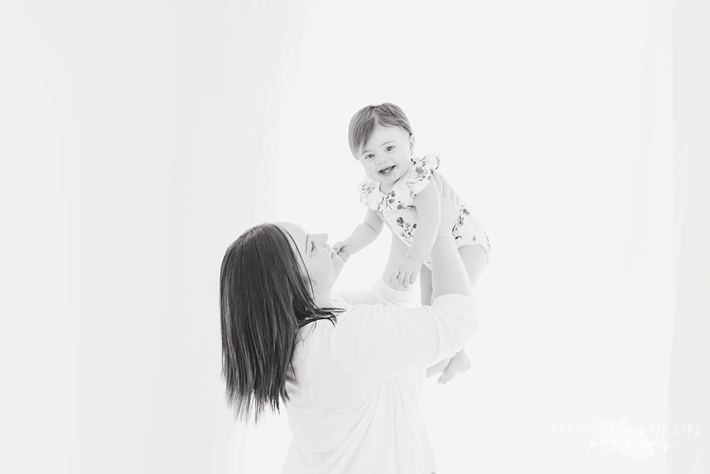 mama lifts her baby up as she smiles at the camera