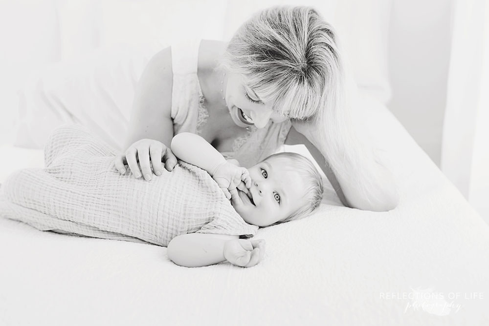 beautiful mama looking at her little boy smiling as he sucks on his finger