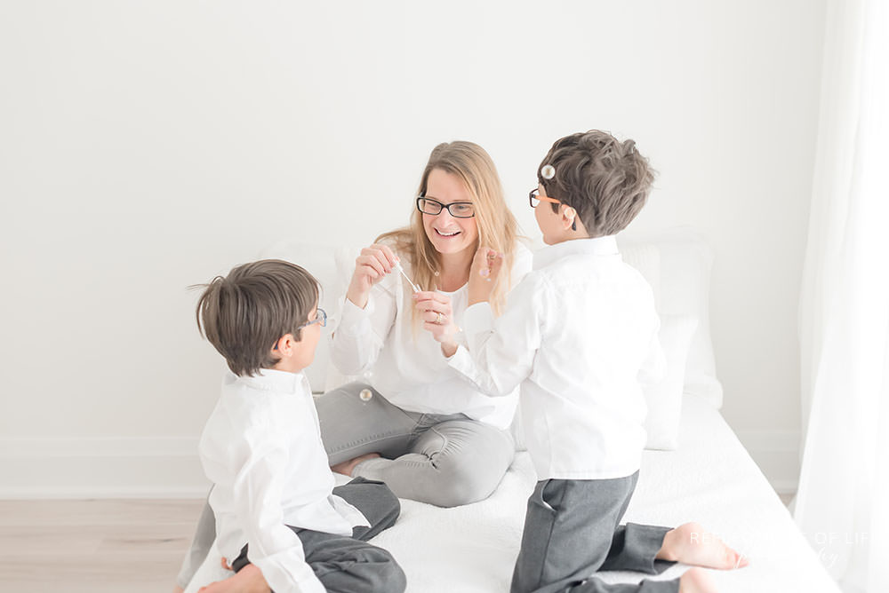 mama with her two boys play with bubbles in natural light studio