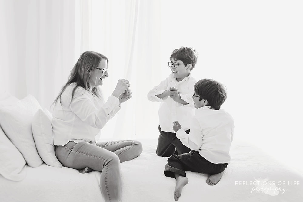 family of three plays on the bed in black and white