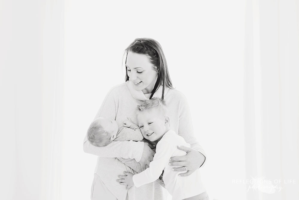 family of three snuggle up in black and white in natural light studio