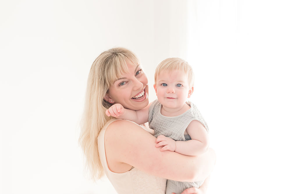 mama and son smile at the camera in natural light studio