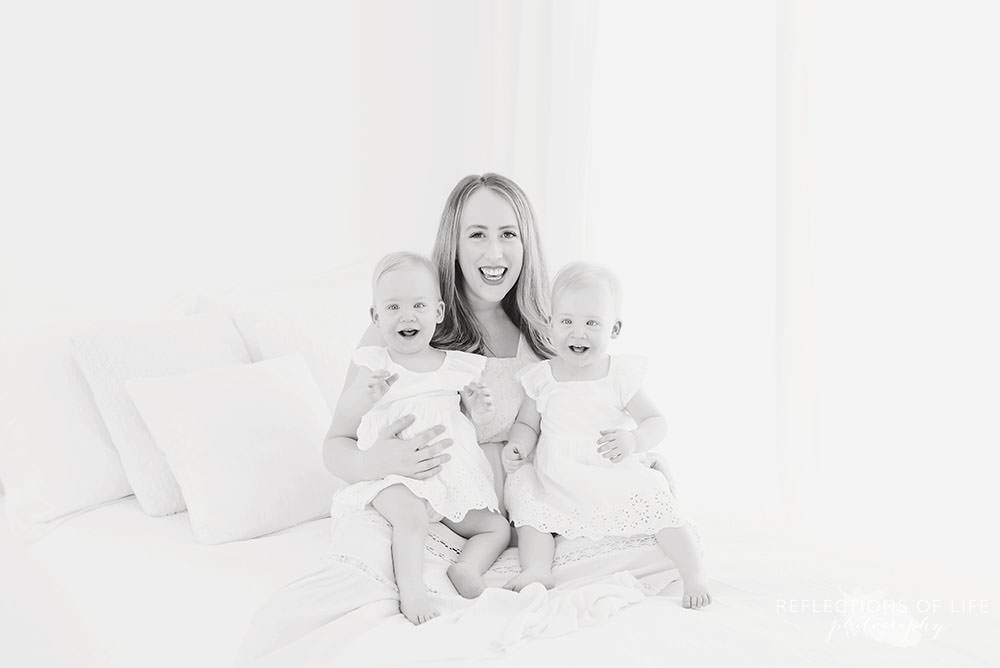 twins and their mama smile at the camera in black and white