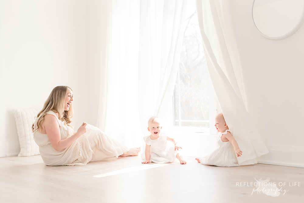 mama plays with her twins behind the drapes