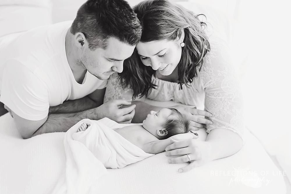 mom and dad smile at baby in black and white
