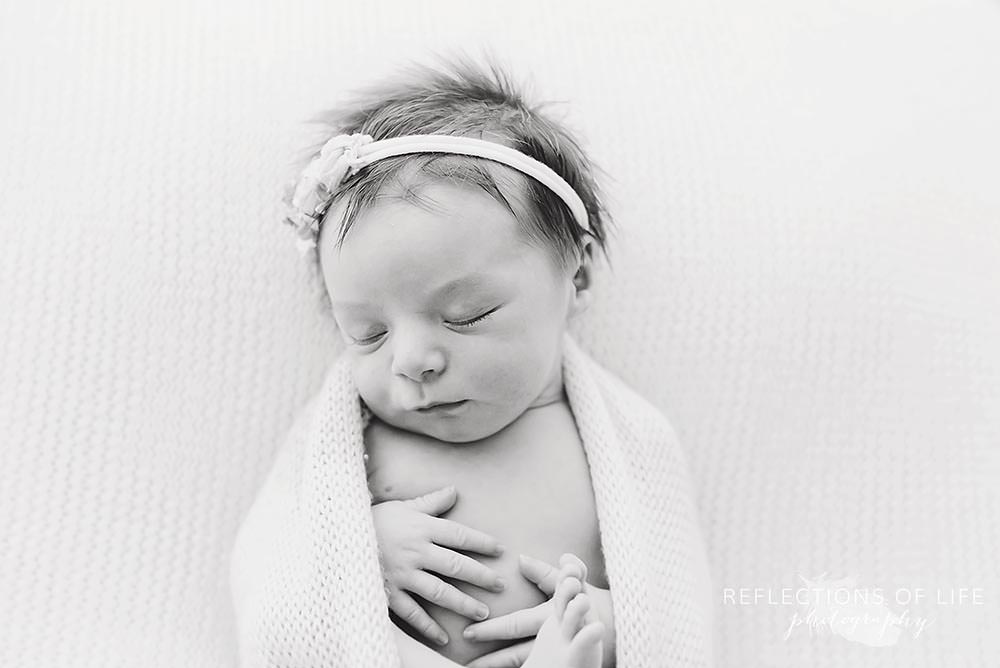 close up of sleeping baby in black and white with their hands on their chest