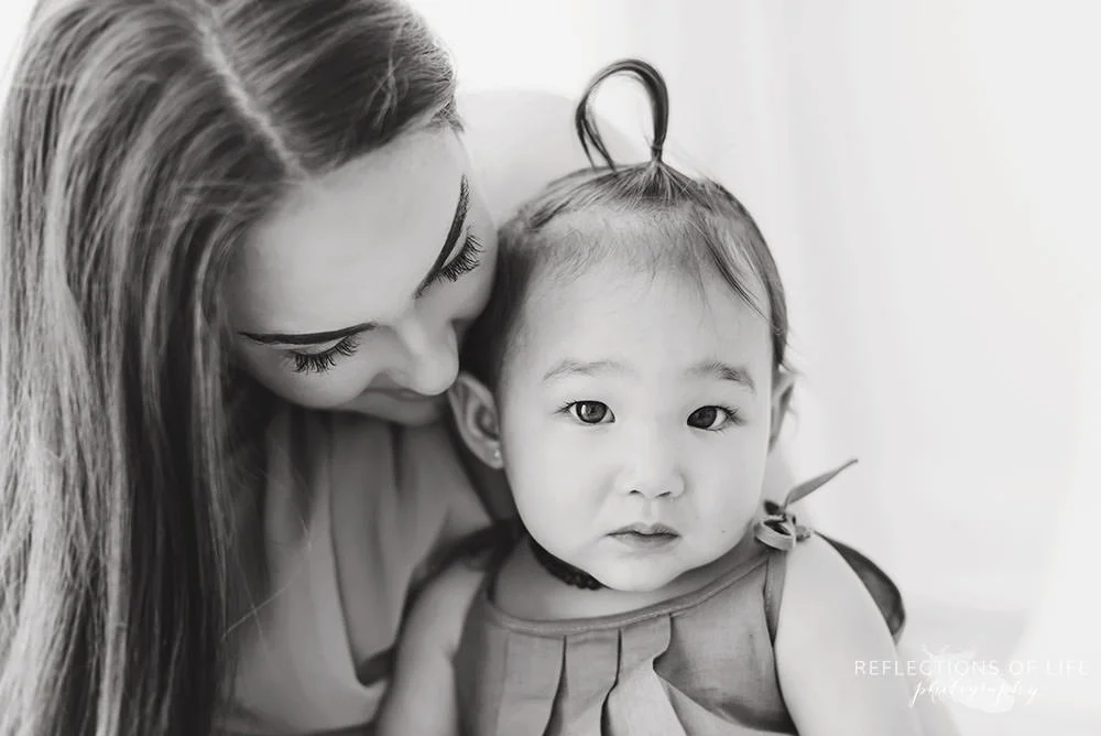 little girl looks at the camera with her mama in black and white