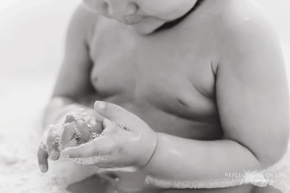 closeup of baby playing with bubbles in black and white