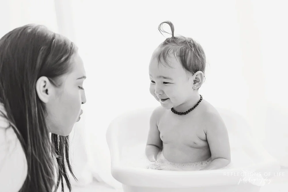 mama blows on her little girl in black and white