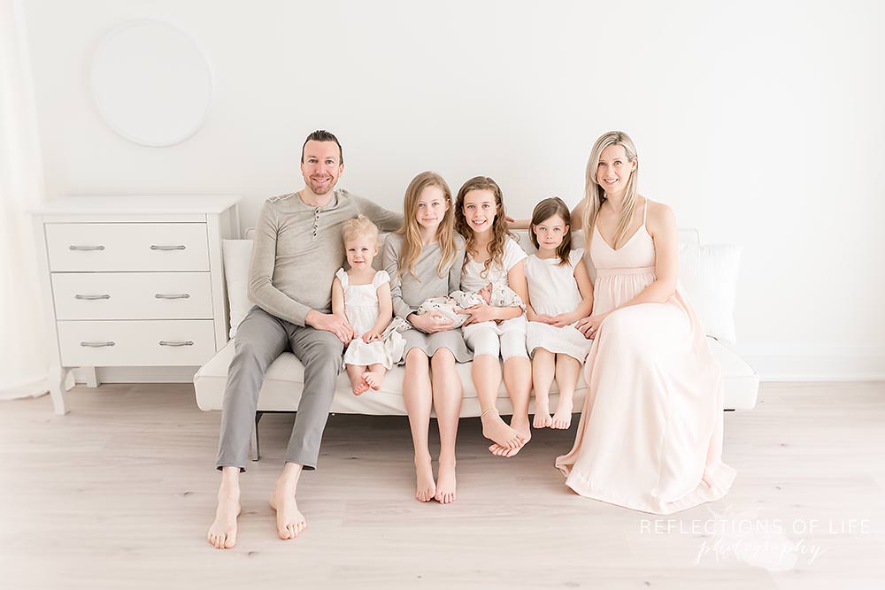family of seven sits on the couch and looks at the camera