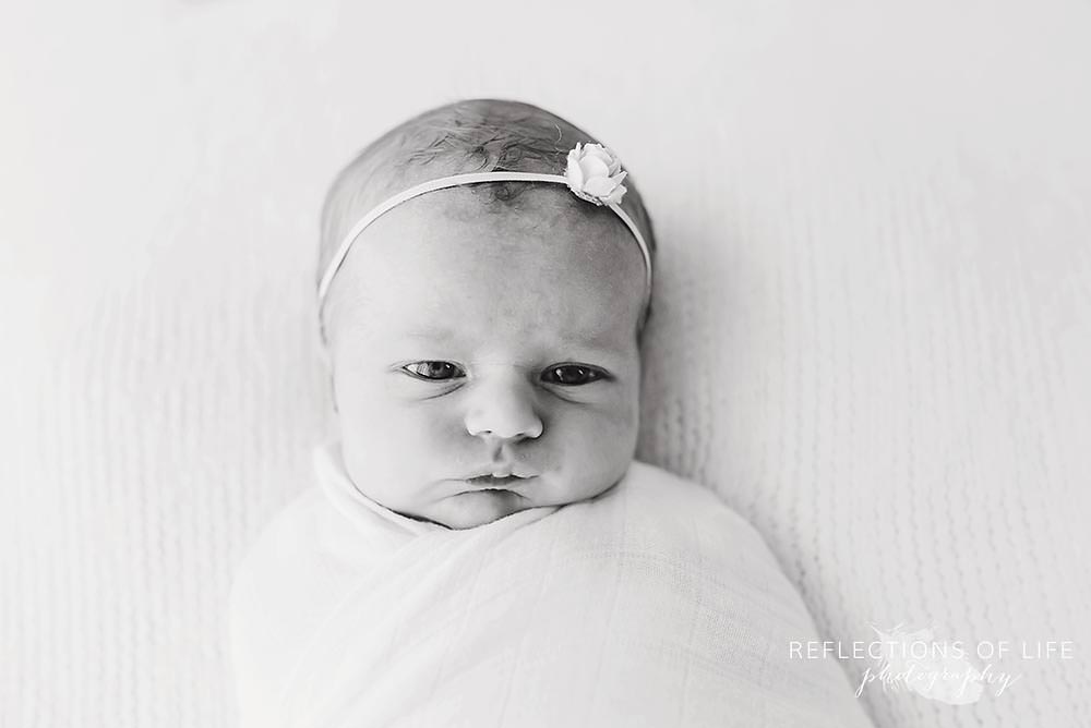 little girl looks at the camera with flower bow in black and white