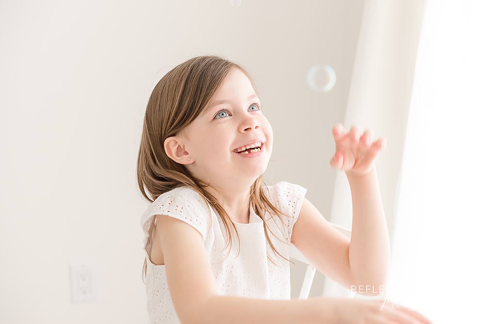 little girl plays with bubbles and laughs