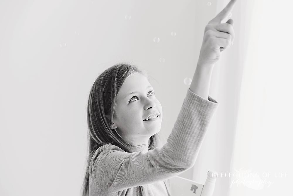 young girl plays with bubbles in black and white