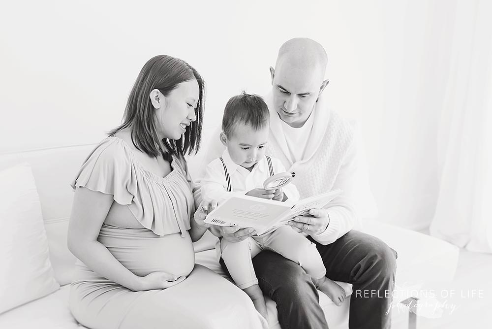 family of three read a book on a couch in black and white