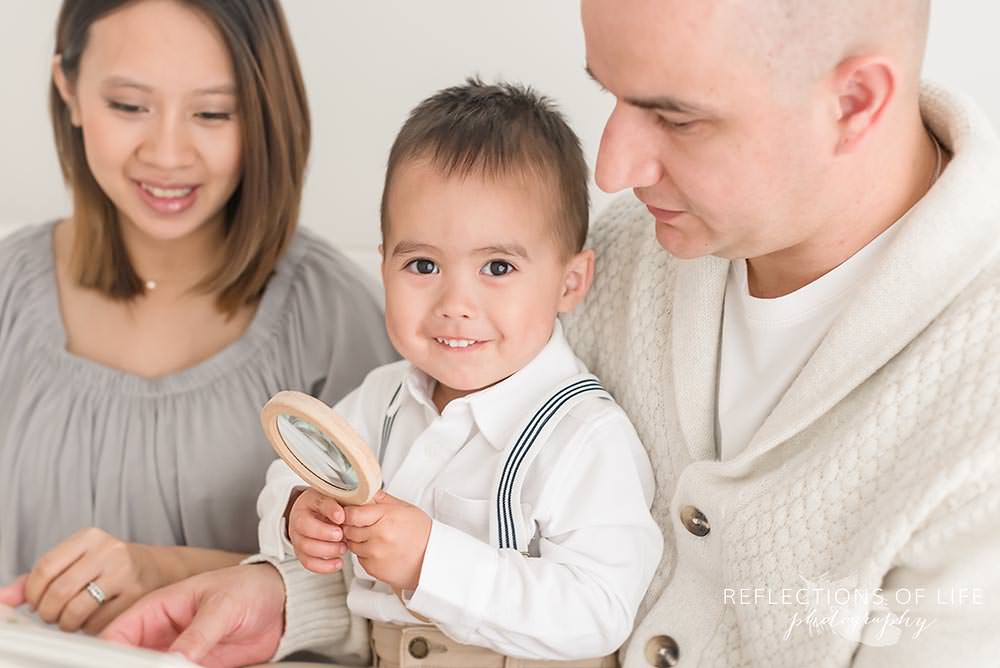 family of three in natural light studio with little boy smiling at the camera