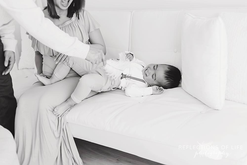 dad tickles his son on the couch with a feather in black and white