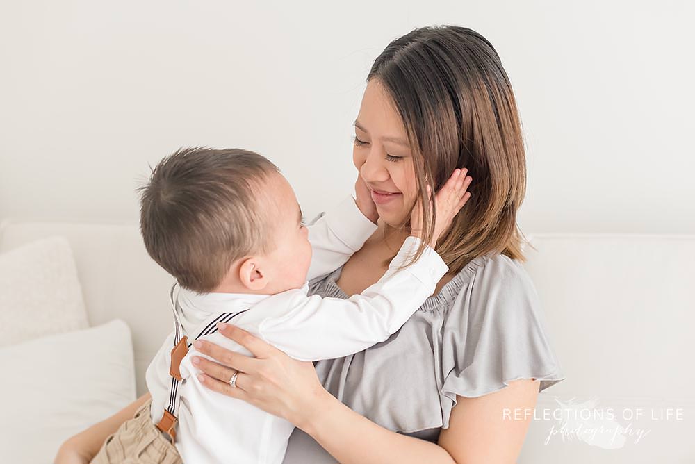 baby squishes his mothers face in natural light studio