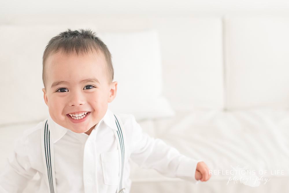 little boy runs and smiles at the camera in natural light studio