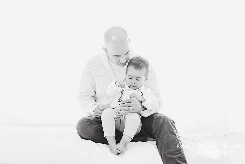 father and son play with bubbles together in black and white