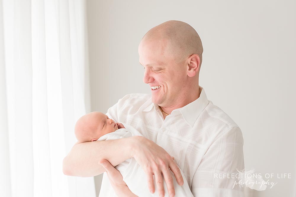 father holds his baby as he smile at him in ontario