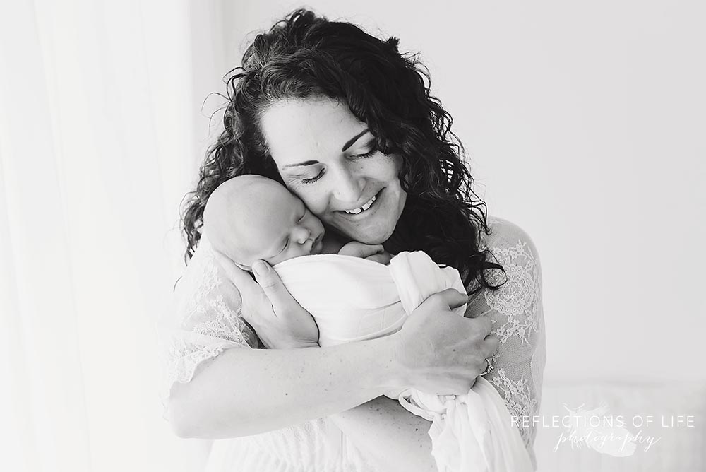 mama cuddles her baby and smiles in black and white