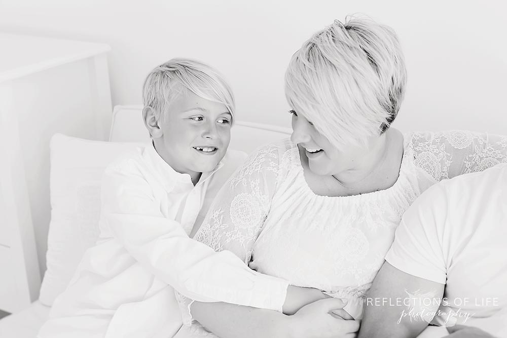 little boy hugs his mama on the couch in black and white in ontario