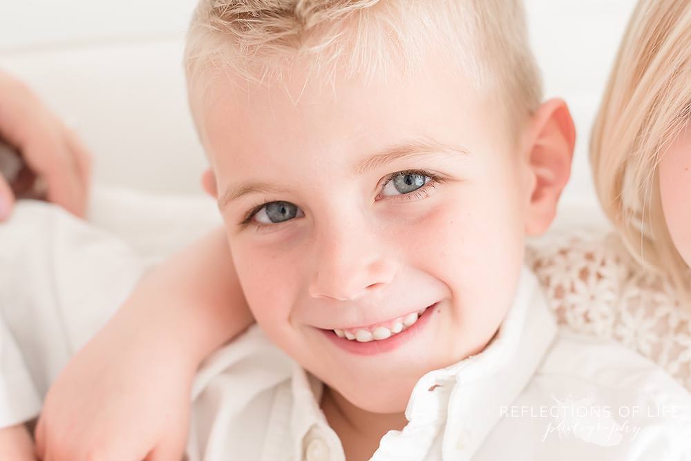 close up of little boy smiling while his sister has her arm around him