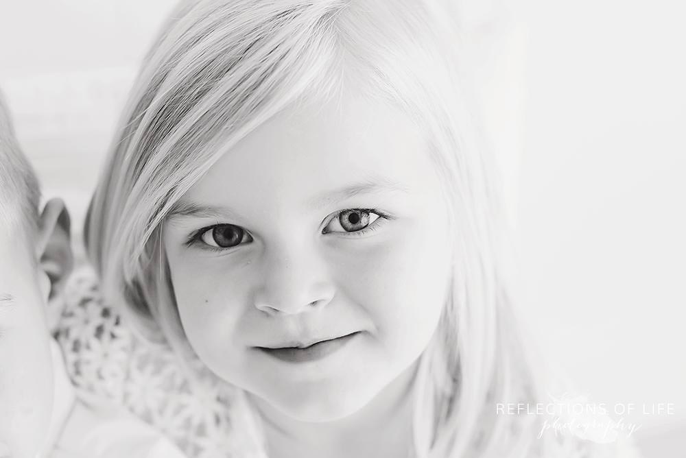 little girl smirks at the camera in natural light studio black and white