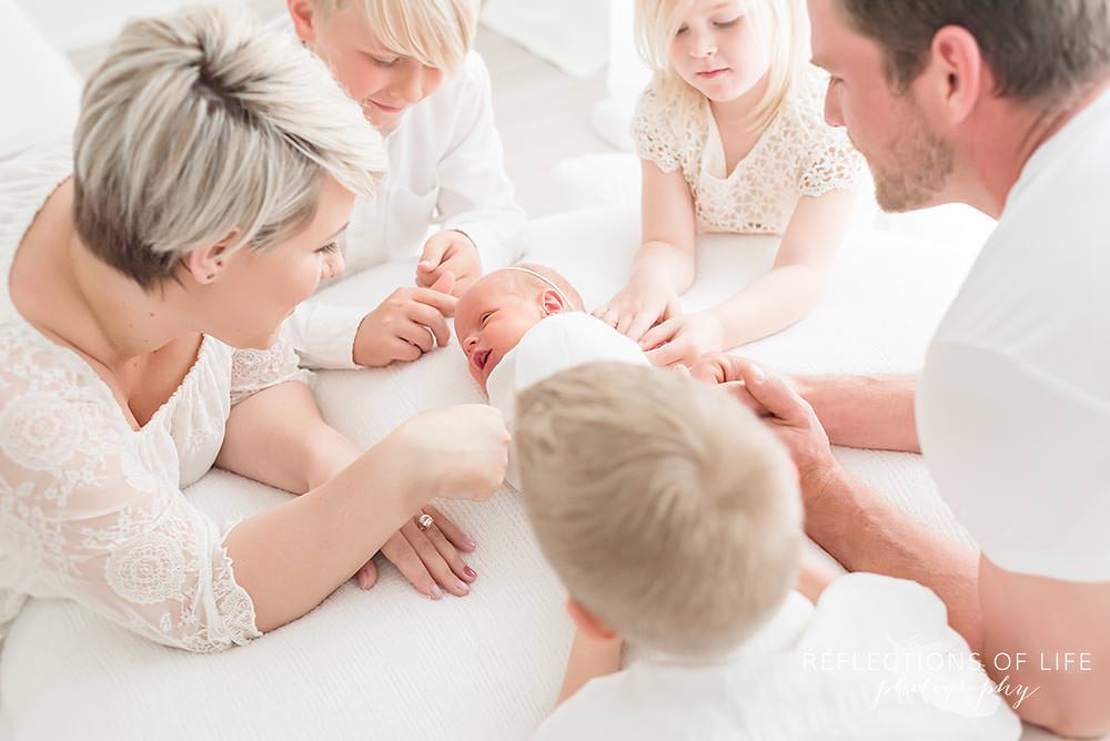 family sits around their new sibling and they all touch her affectionately in niagara