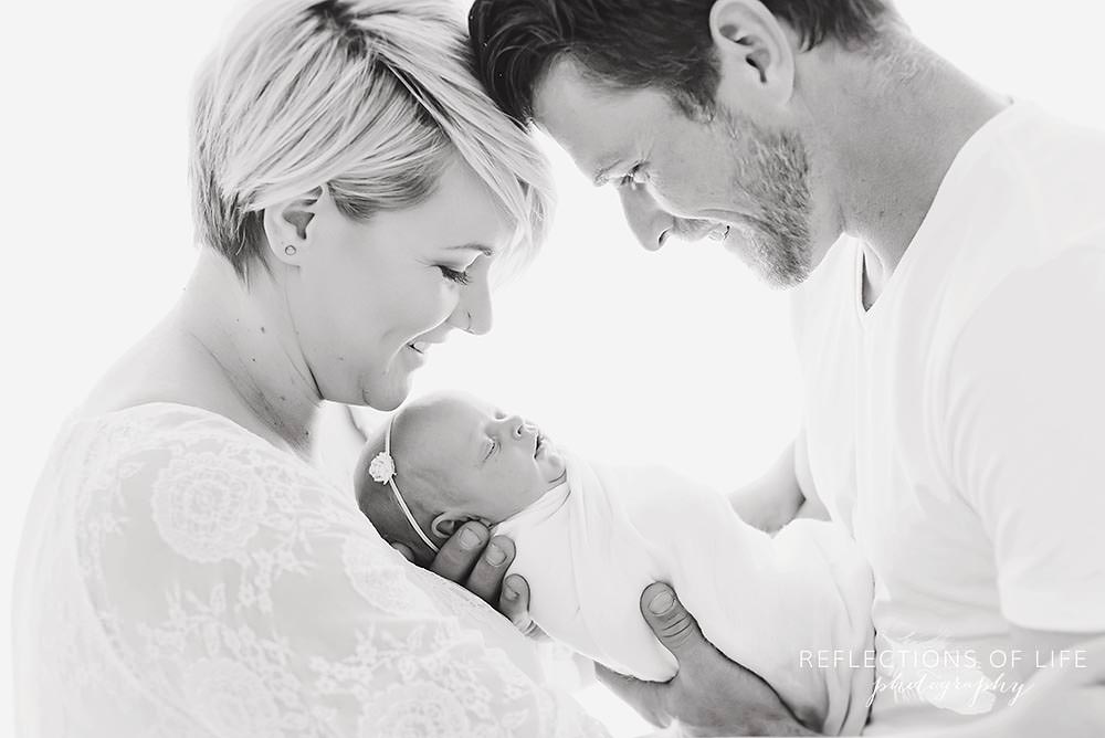 new parents smile at their new baby in black and white