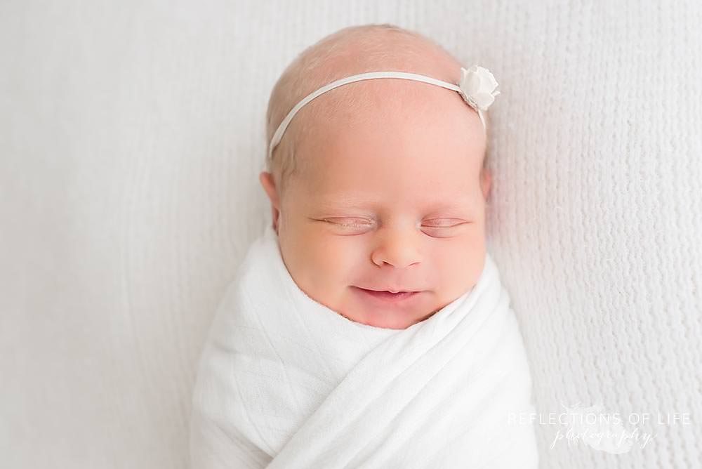 swaddled newborn smiles in natural light studio