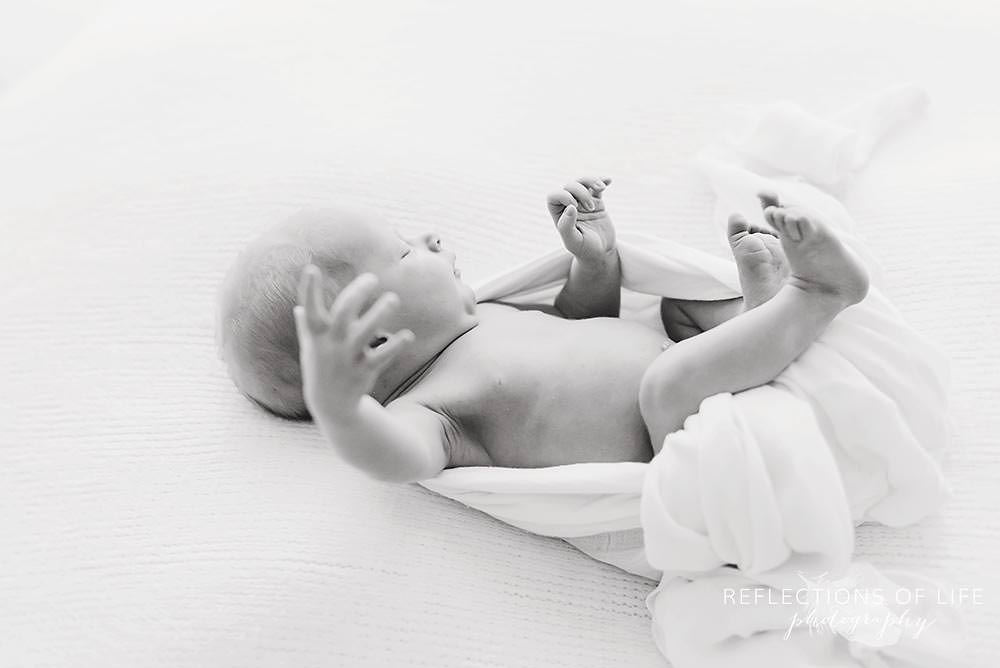 newborn baby girl moves around in her sleep in black and white