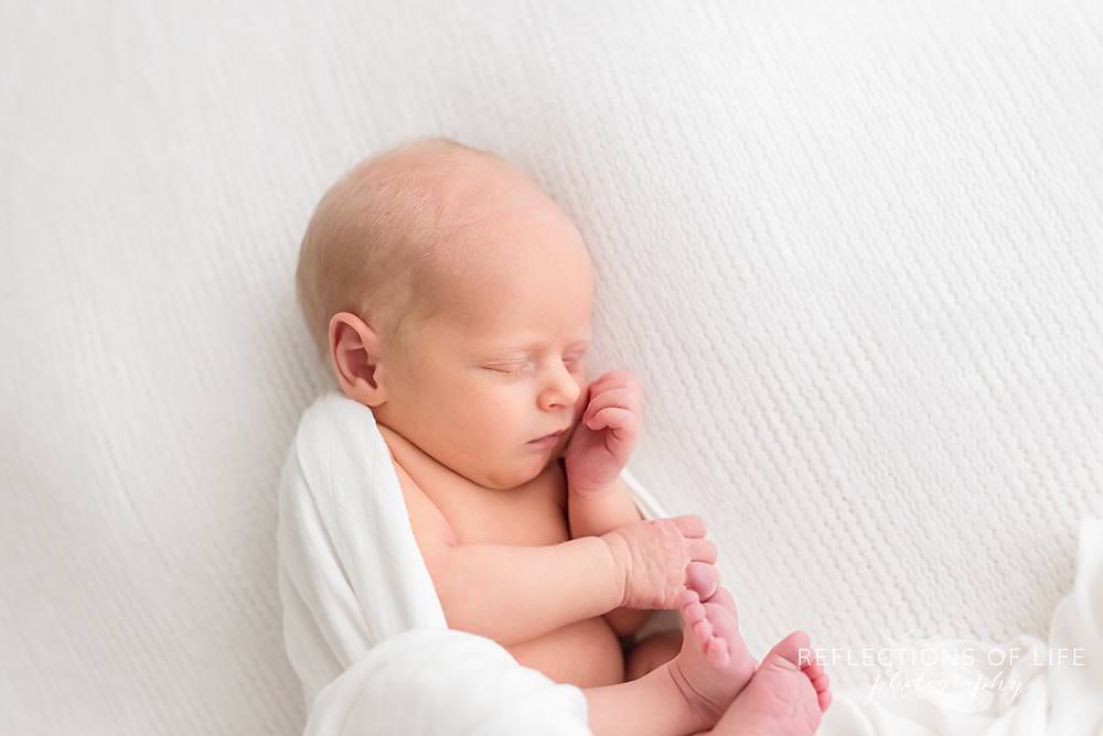 curled up newborn sleeps soundly in natural light studio