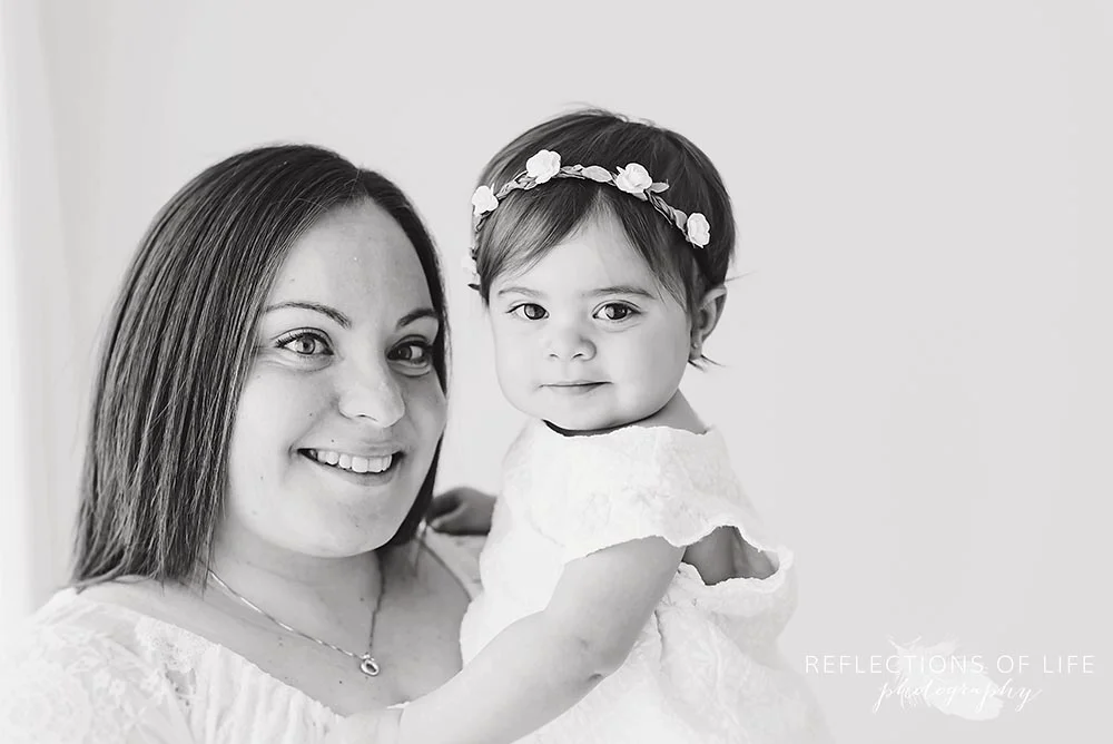 close up of mama and baby smiling at the camera in black and white