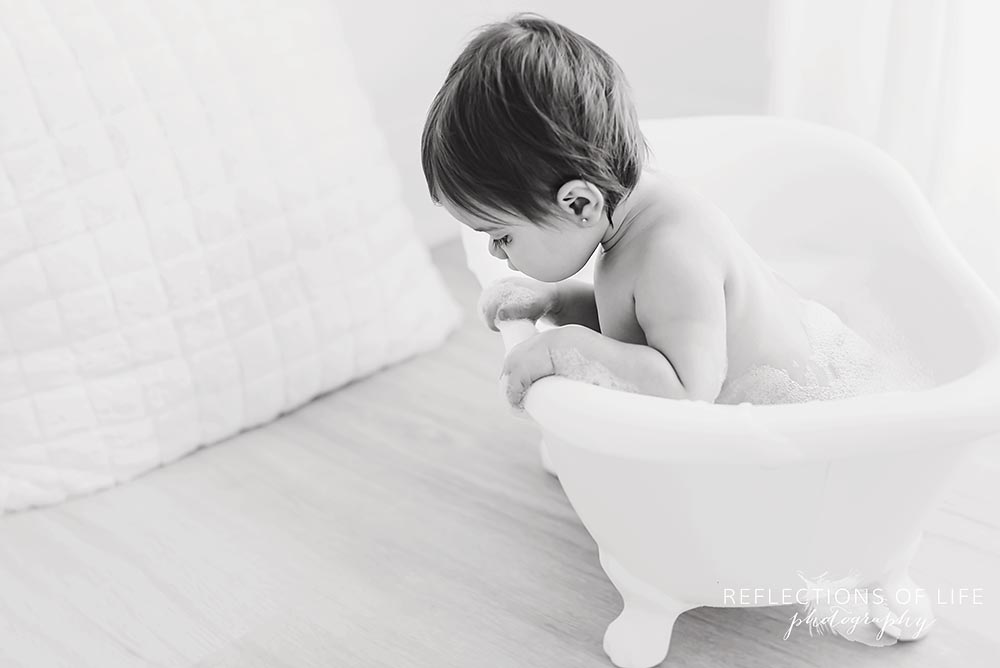 baby looks out of the bathtub in black and white in grimsby