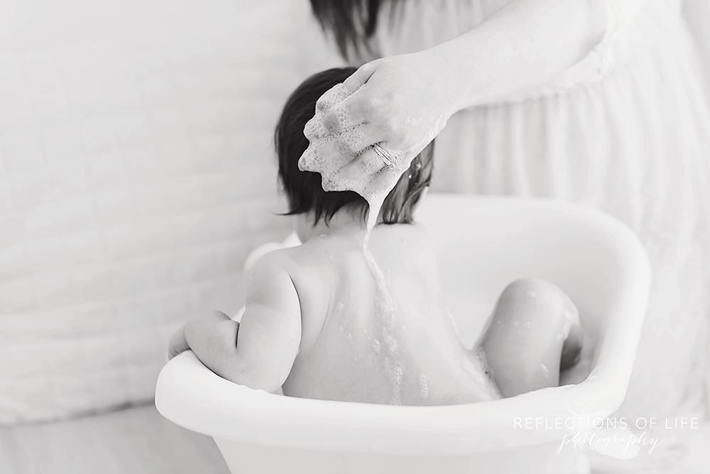 mama washes baby's back in black and white in ontario